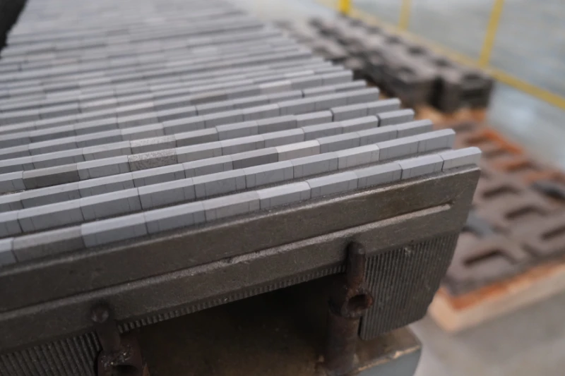 Automated induction welding station joining carbide inserts to a snow plow blade